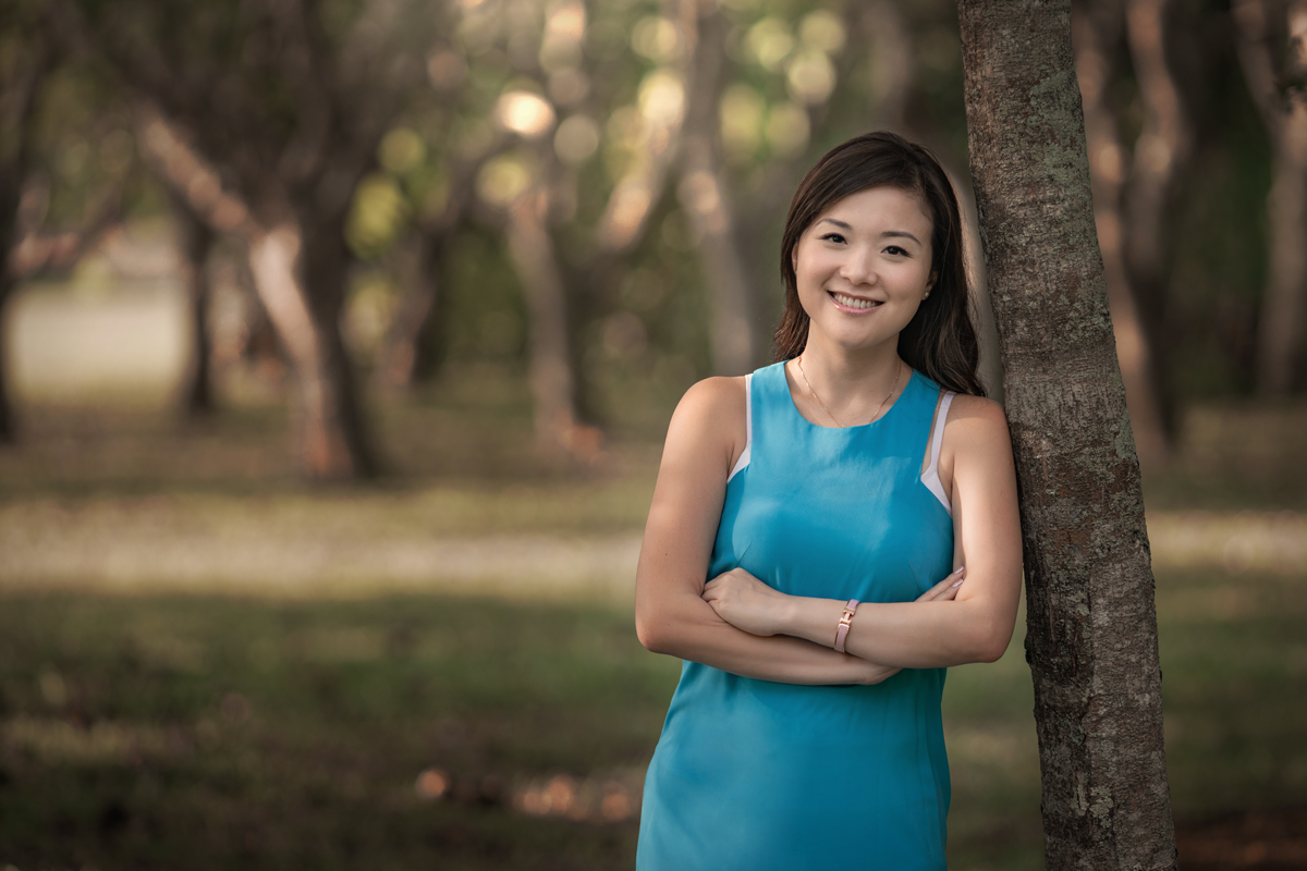 Radiant woman smiling, posing beside a tree in captivating photoshoot by Bernard Sim Photography